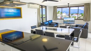 Una sala de estar moderna con comedor, ventanas amplias y vistas, y un televisor de pantalla plana.