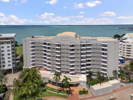Un hotel de varios pisos con balcones, un estacionamiento y vistas al océano.