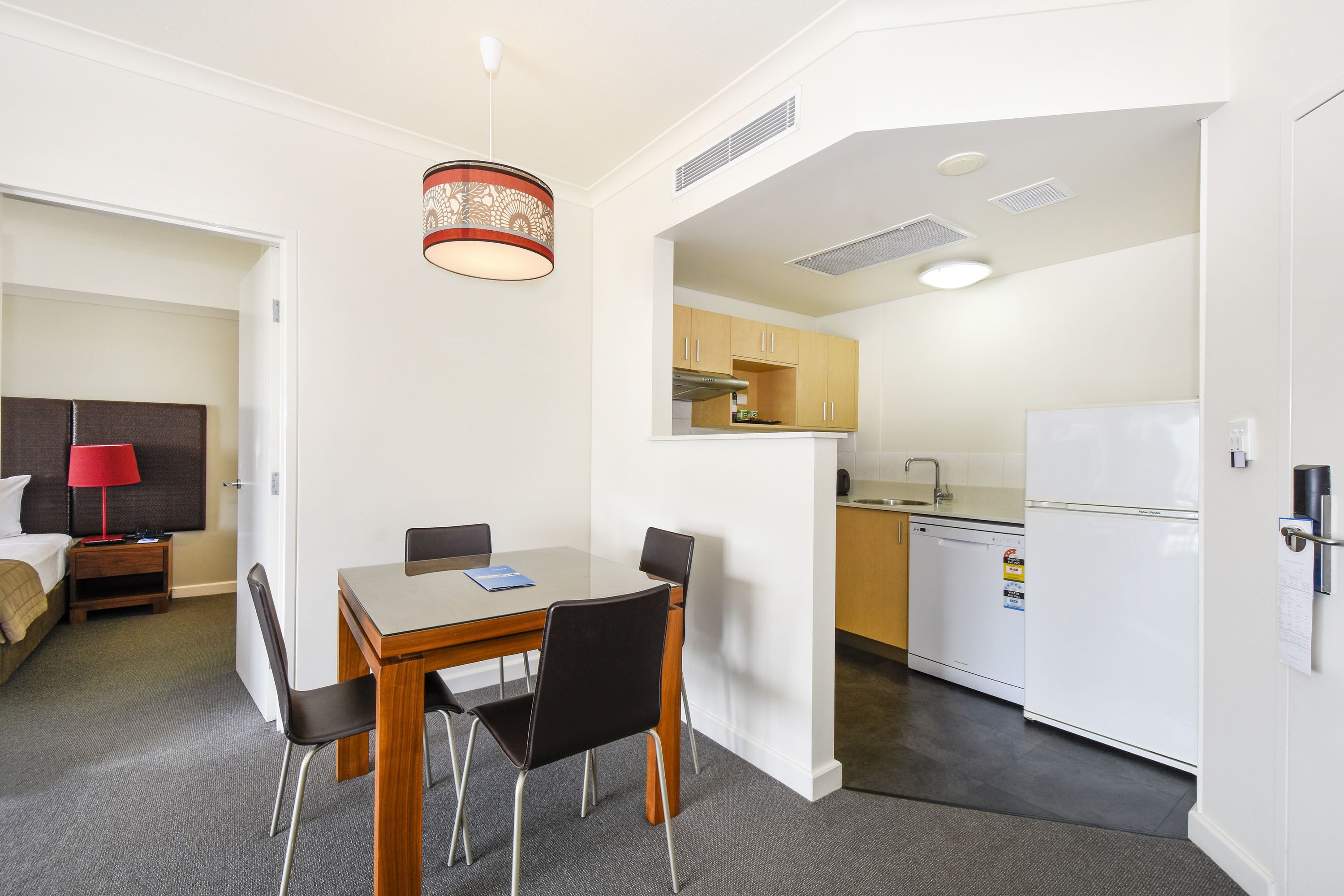 Une chambre d’hôtel compacte comprenant un coin repas, une kitchenette et une chambre à coucher séparée.