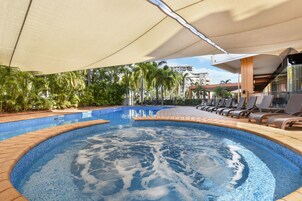 Una piscina con jacuzzi, sillas de descanso y palmeras.