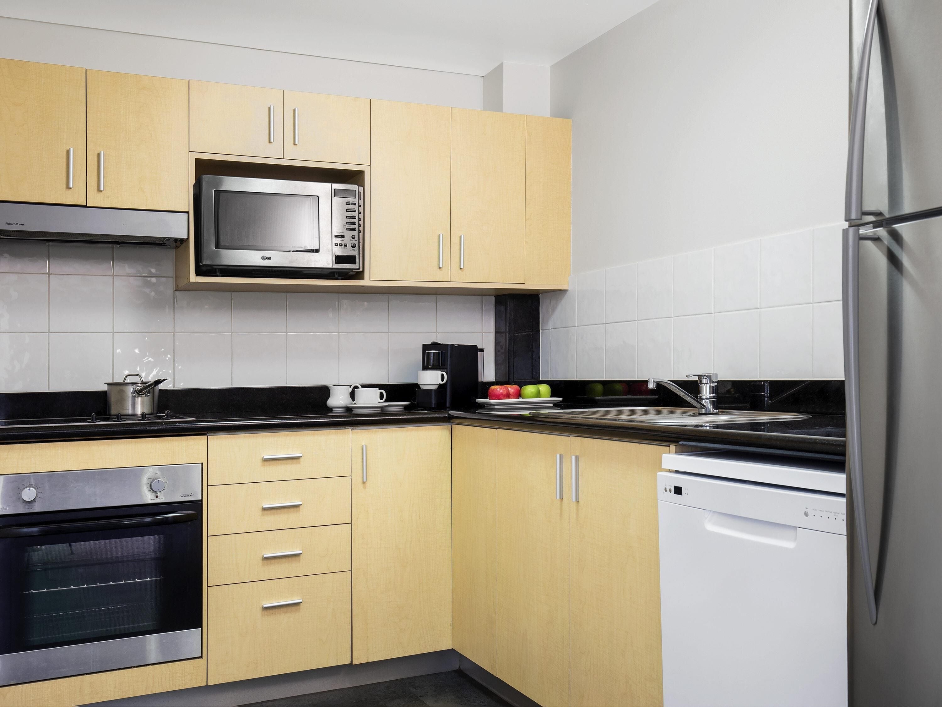 A modern kitchen with wooden cabinets, a built-in microwave, a stove, and a dishwasher.