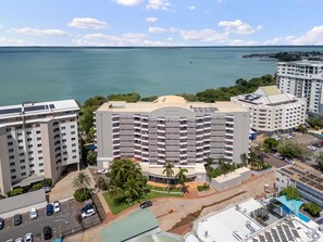 Een hotel met meerdere verdiepingen, een centraal binnenterrein, parkeerplaats en uitzicht op zee.