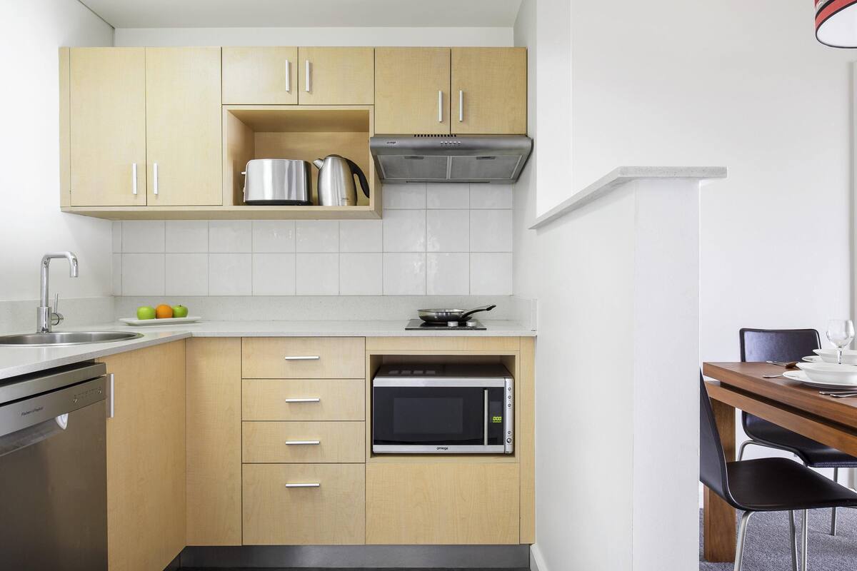 A modern kitchen with wooden cabinets, a stainless steel sink, a microwave, and a gas stove.