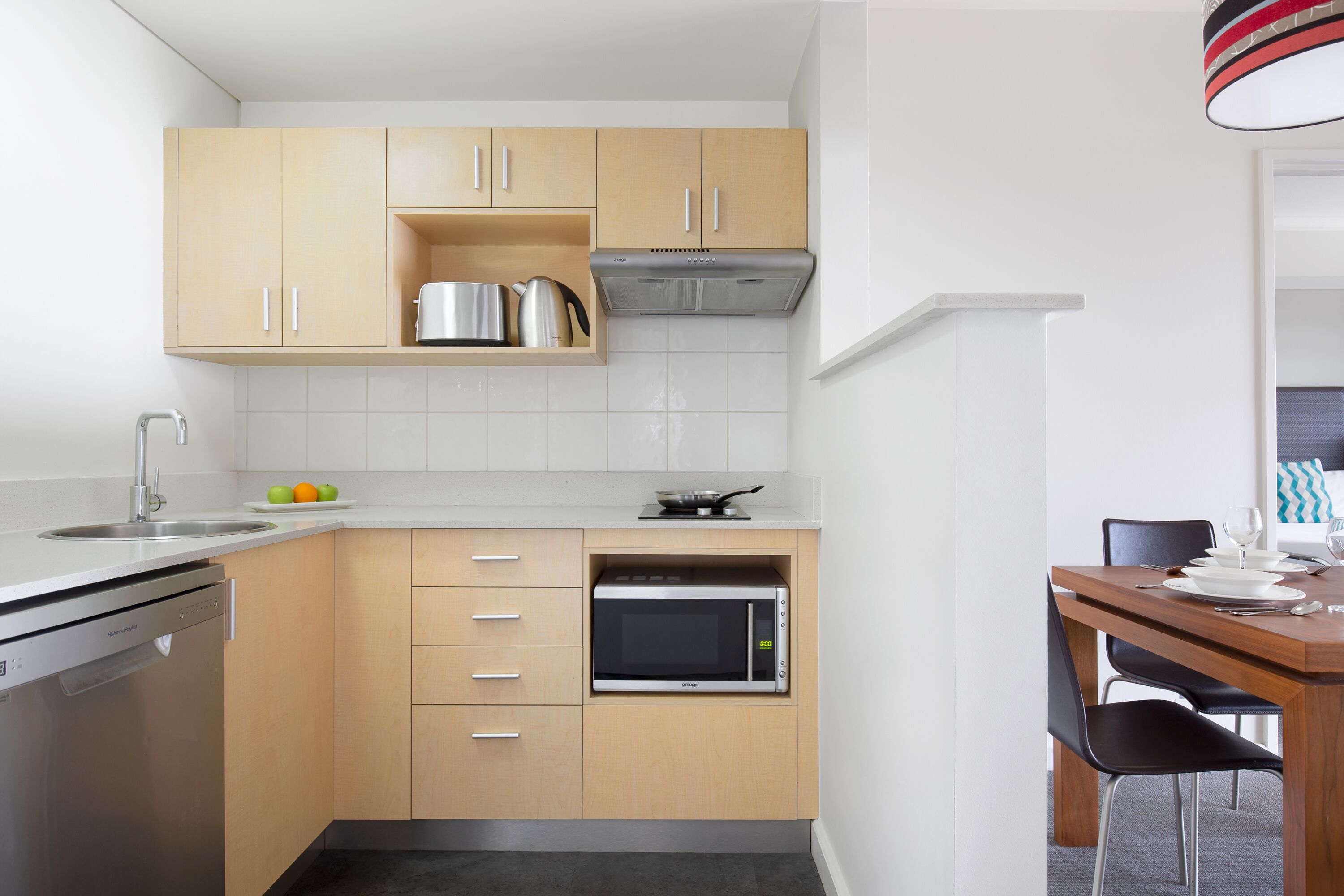 Una cocina funcional con lavavajillas, microondas y armarios de madera.