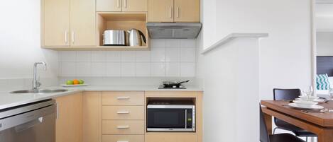 Una cocina funcional con lavavajillas, microondas y armarios de madera.