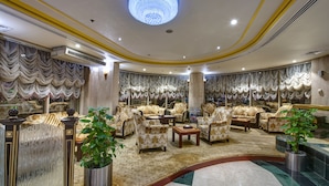 A luxurious lobby with ornate curtains, plush seating, and a grand chandelier.