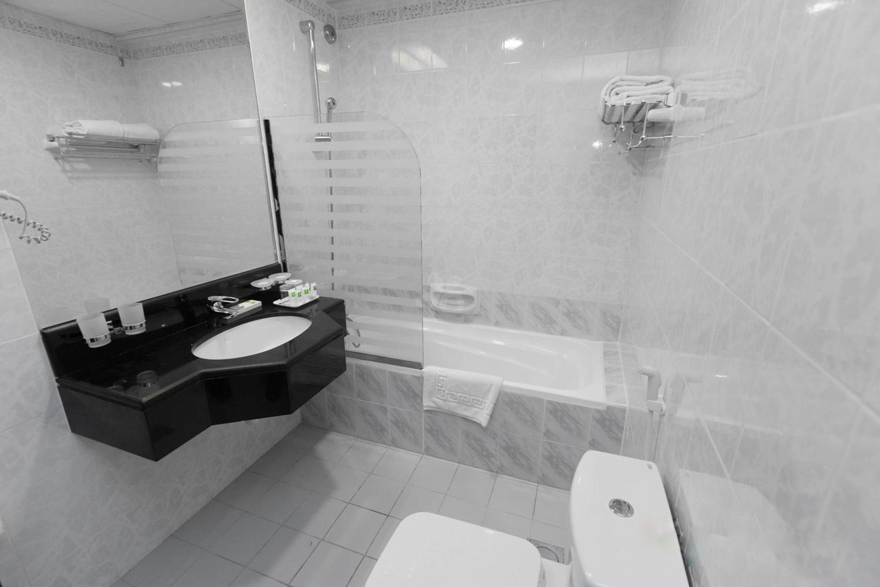 A modern bathroom with a black vanity, a white sink, a glass shower enclosure, and a white toilet.