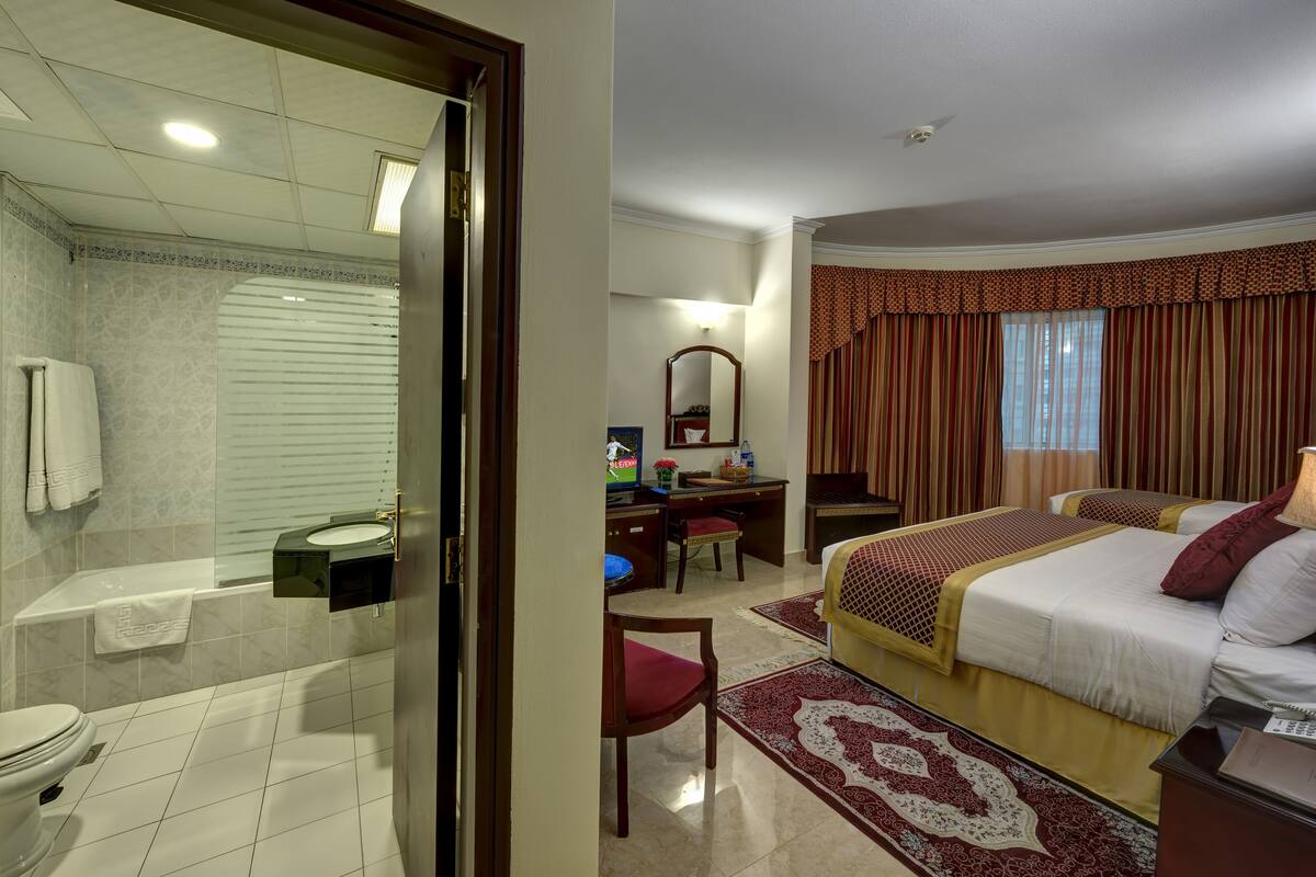 A hotel room with a bathroom, a desk, a bed, and a chair.