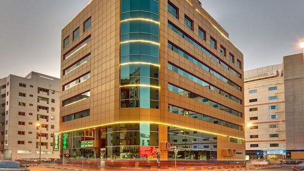 A modern hotel with a curved facade, multiple floors, and illuminated windows.