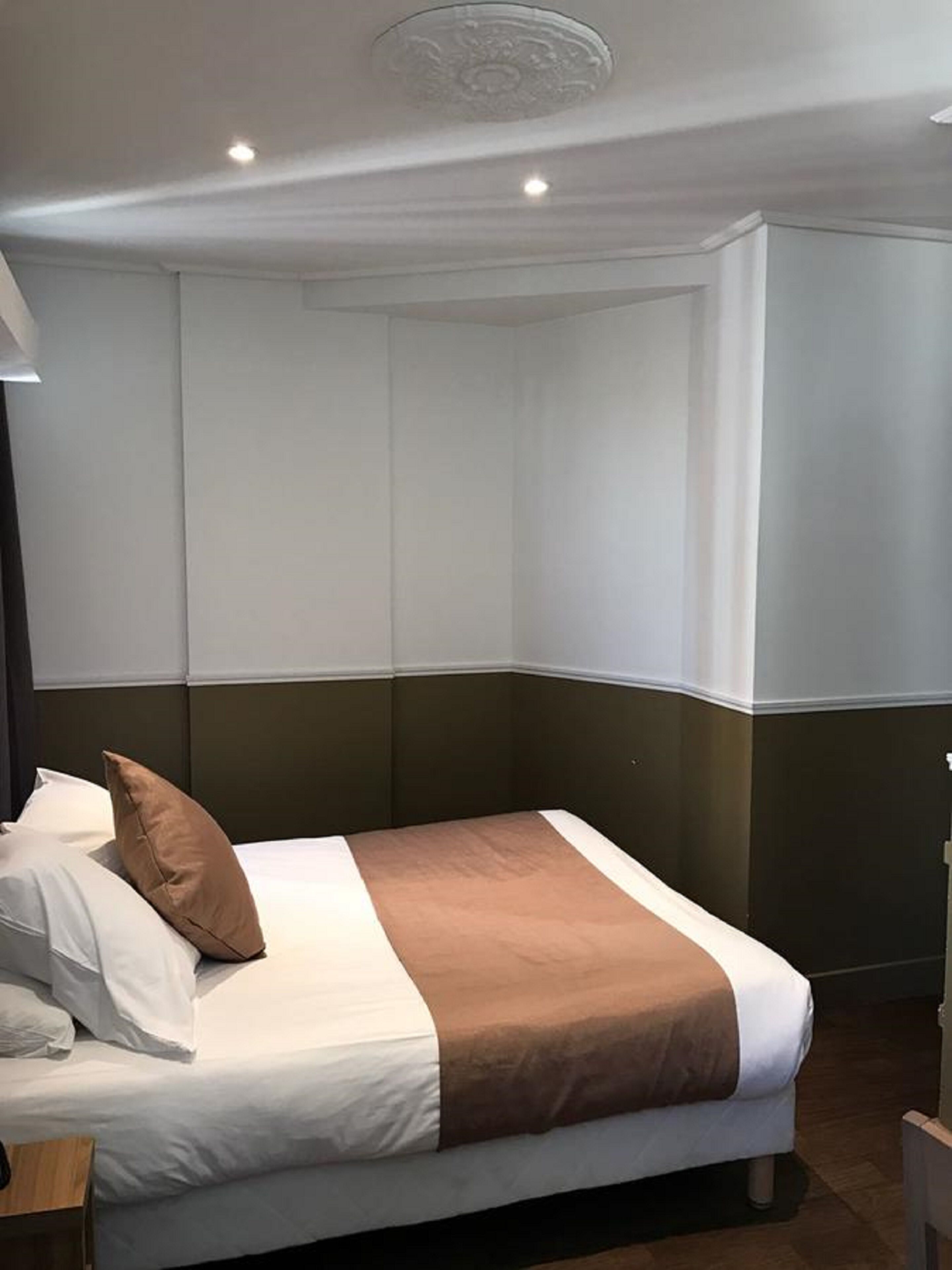 A hotel room with a bed, white walls, and a dark headboard.