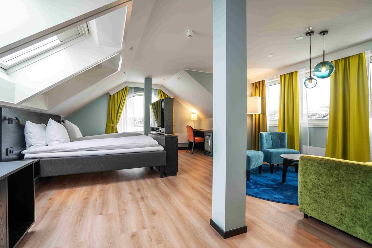 Une chambre d’hôtel moderne avec un lit en mezzanine, un bureau, une chaise, un canapé et une table à manger.