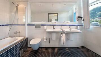 Un baño moderno con bañera, dos lavabos, inodoro y ducha.
