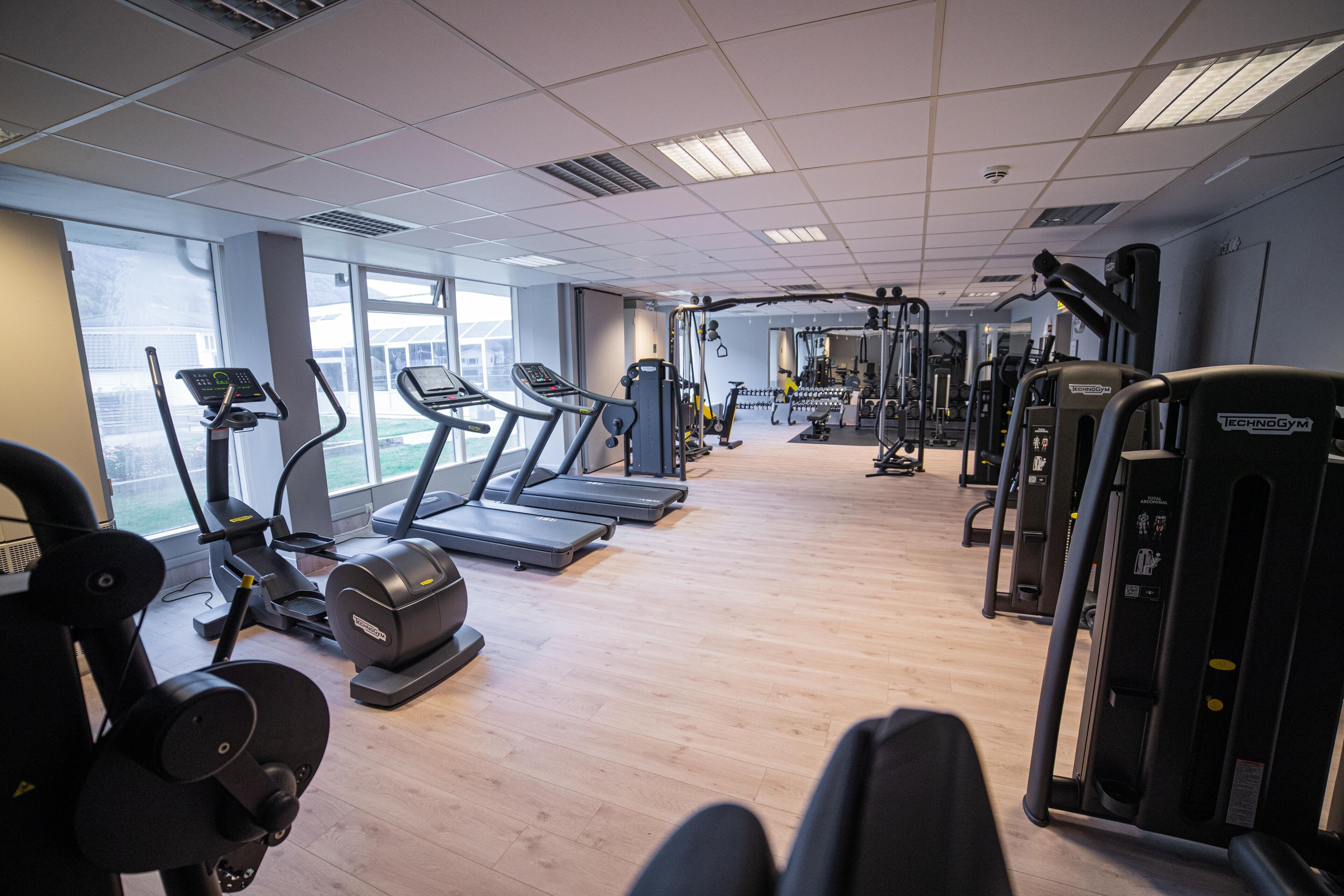 Ein Fitnessstudio mit Laufbändern, Crosstrainern und Gewichten.