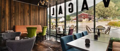 A modern interior with a wooden wall, leather seating, and a view of a building and mountains.