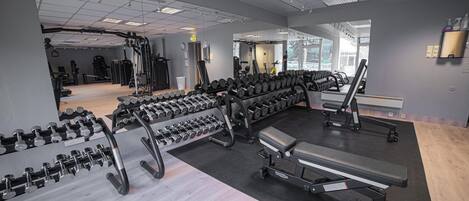 Un gimnasio con diversos equipos de ejercicio, incluyendo pesas y bancos.
