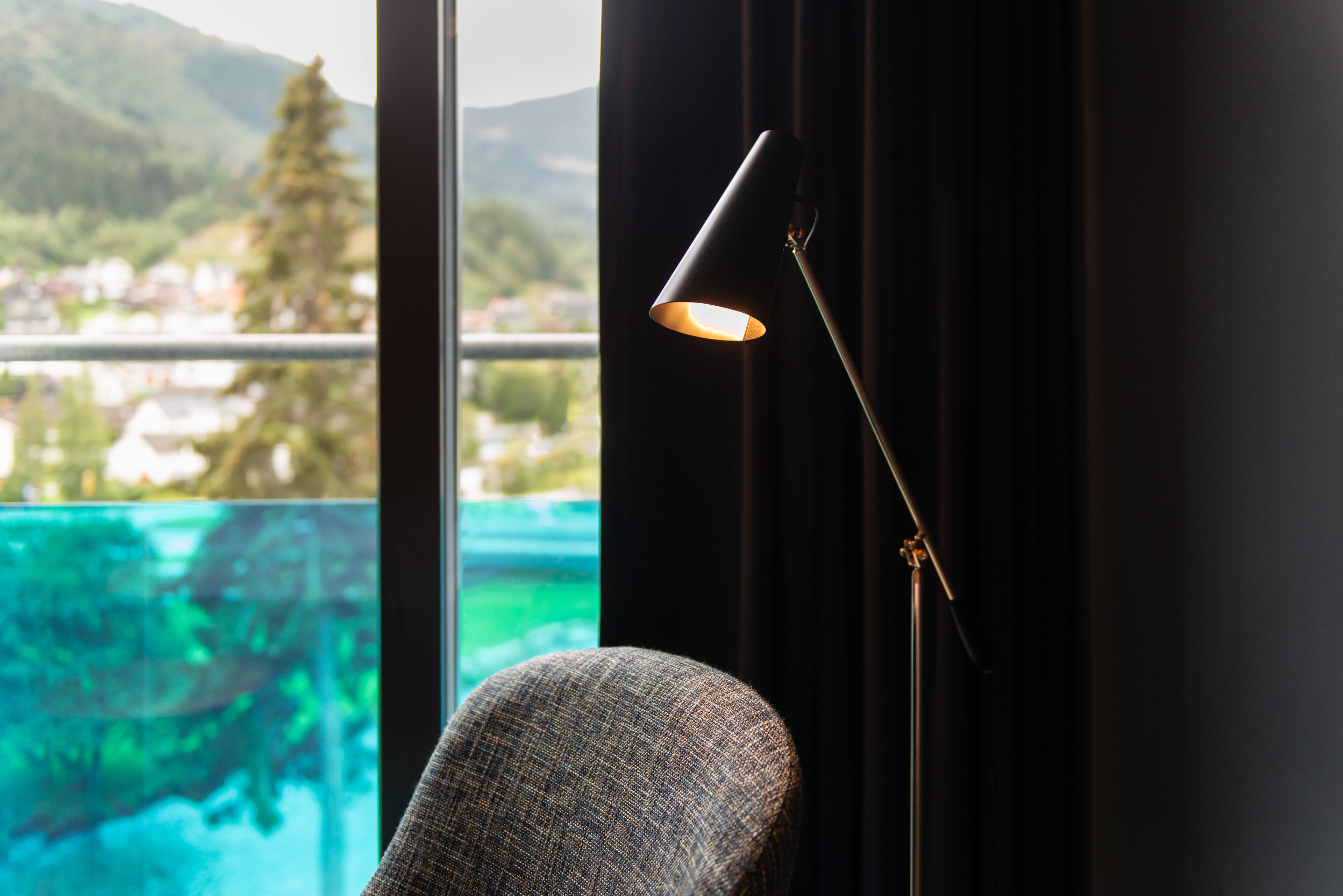 Habitación con vista a un puente y montañas, una silla y una lámpara de pie.