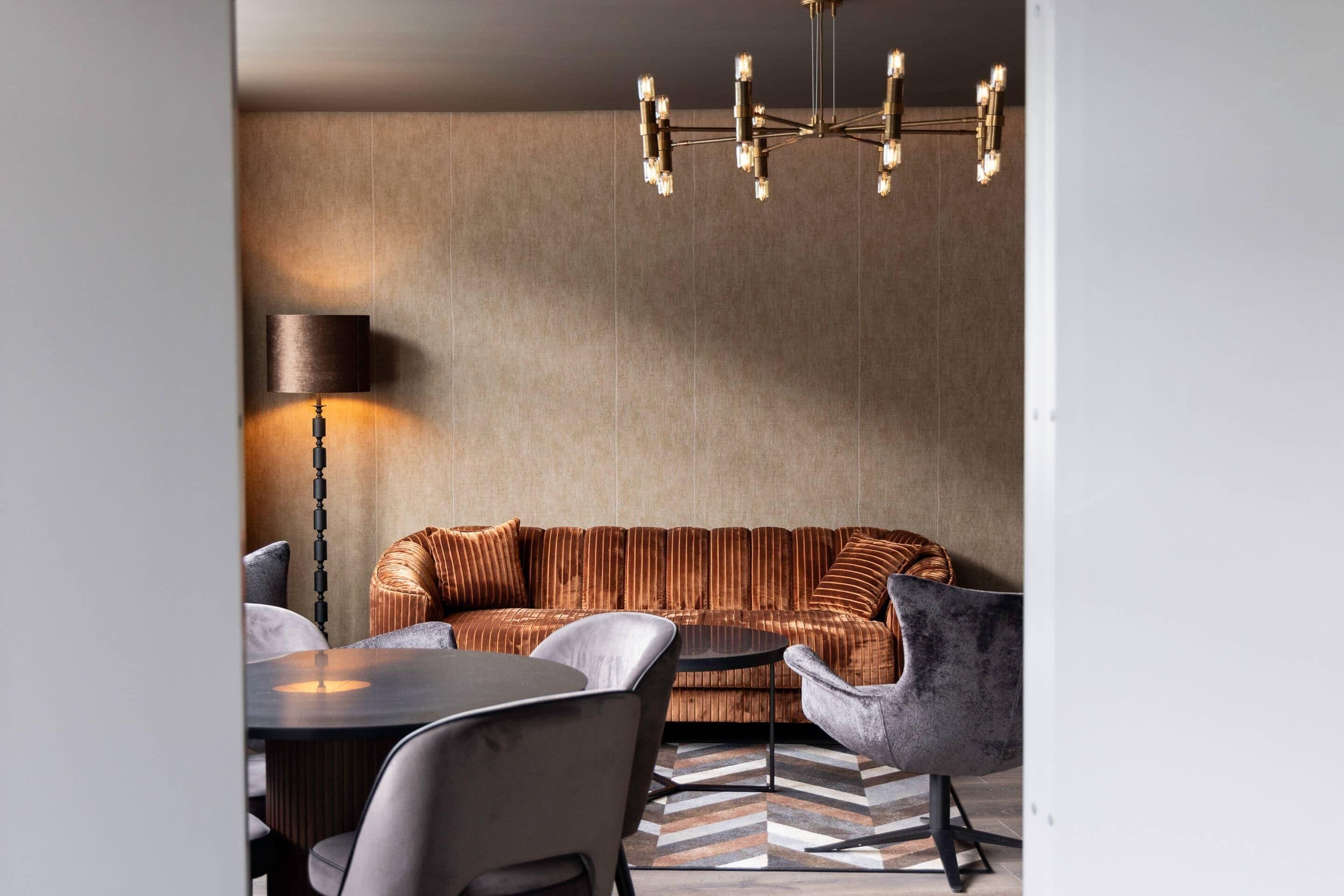 Ein modernes Wohnzimmer mit einer Couch, Sesseln, einem Couchtisch und einer Stehlampe.