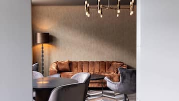 Ein modernes Wohnzimmer mit einer Couch, Sesseln, einem Couchtisch und einer Stehlampe.