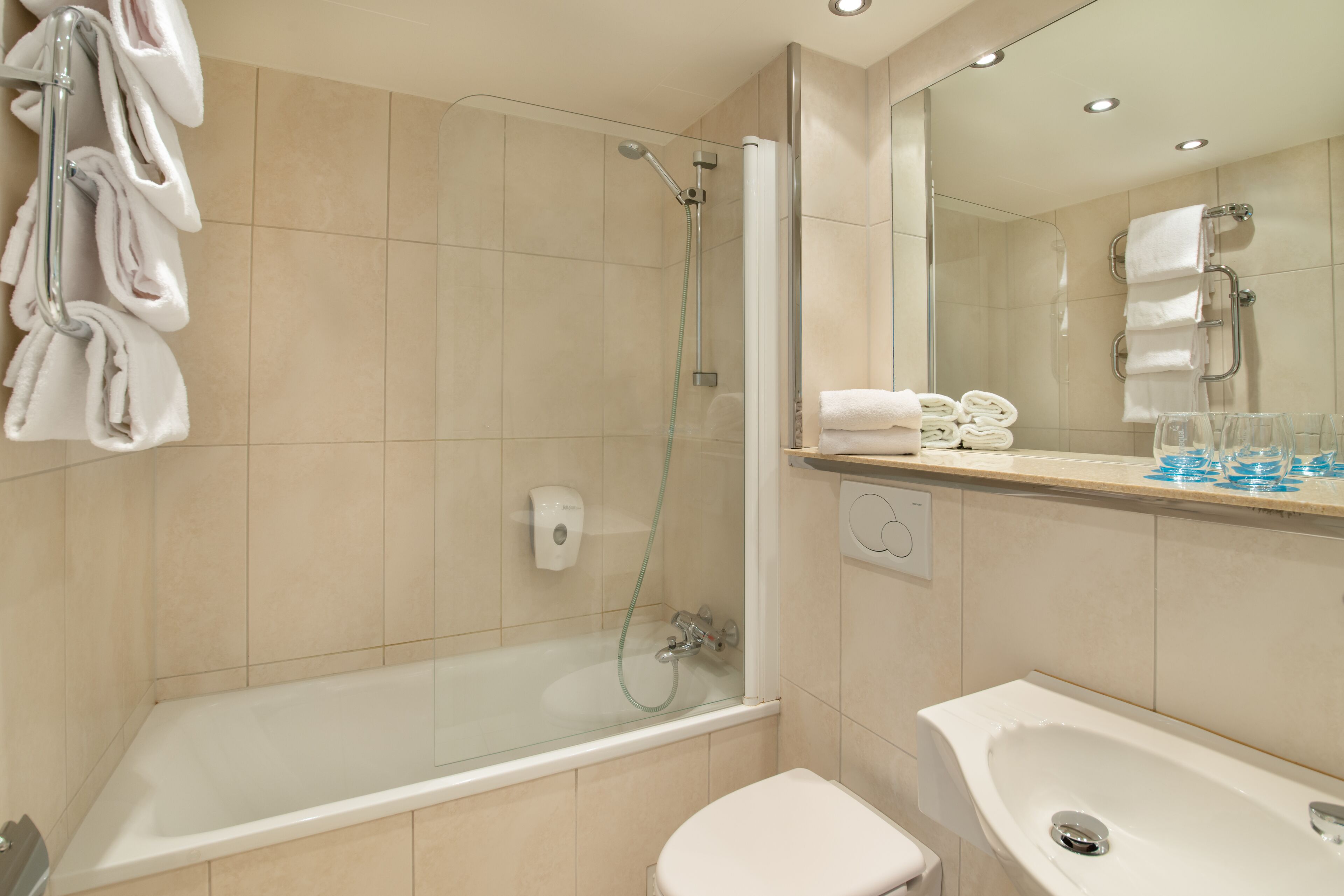 A modern bathroom with a glass-enclosed shower, a white toilet, and a sink with a mirror above it.