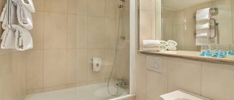 Un baño moderno con ducha envuelta en vidrio, inodoro blanco y lavamanos con espejo.