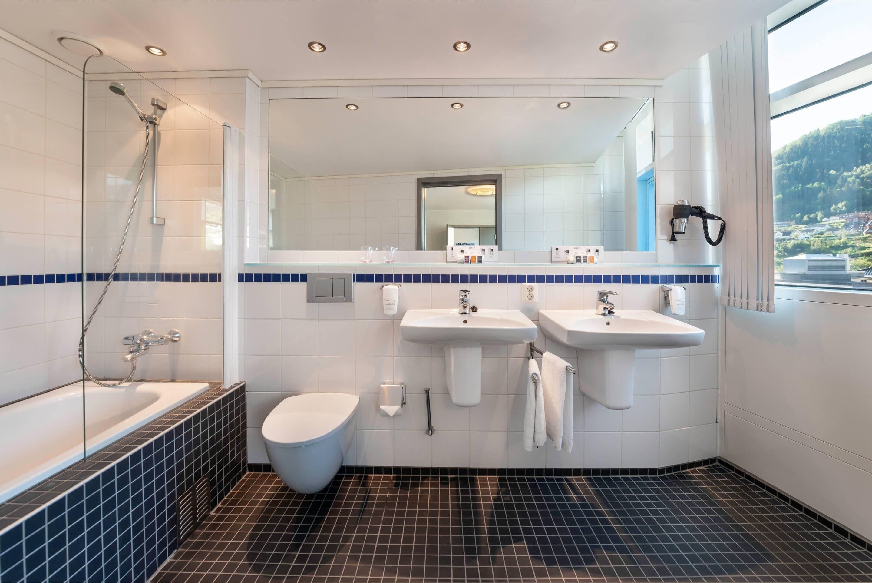 Un baño moderno con bañera, dos lavamanos, inodoro y ducha.