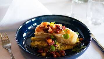 En blå tallrik med en fiskfilé, tärnade grönsaker och örter.