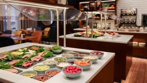 A buffet with various food items and a kitchen area in the background.