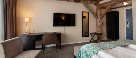 A hotel room with a bed, a desk, a chair, a television, and a mirror.