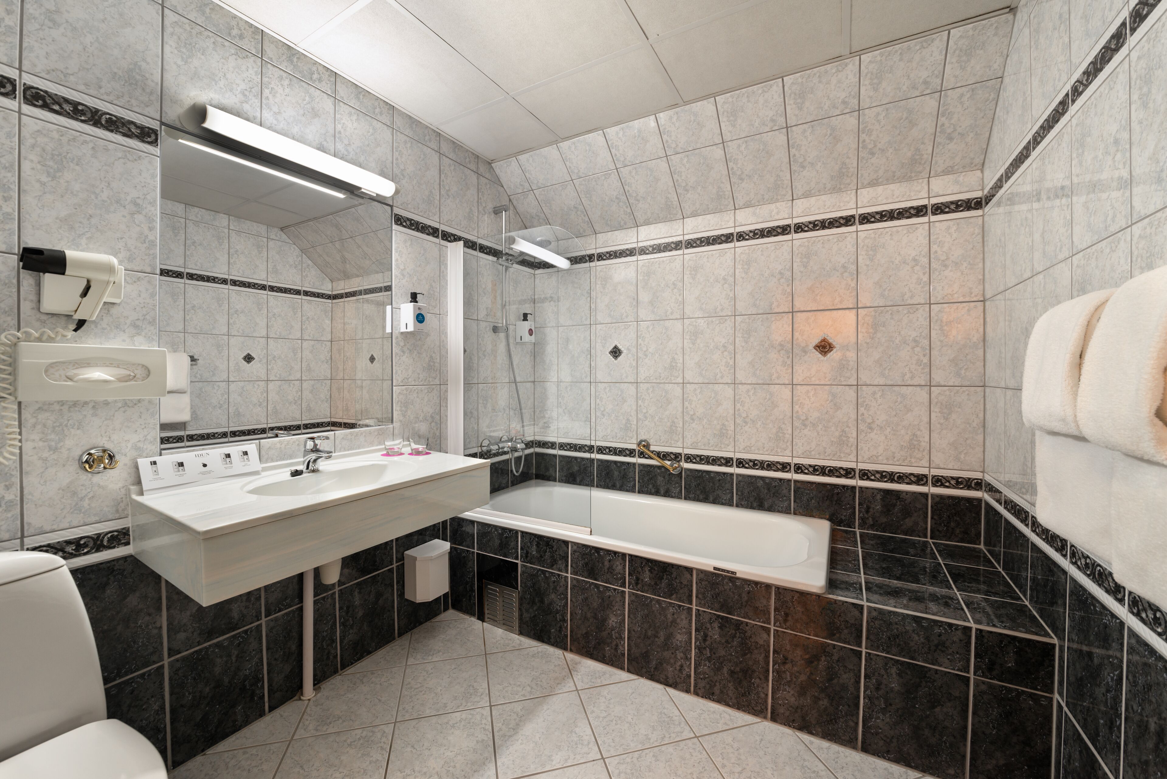 Un bany modern amb una banyera gran, un lavabo amb mirall i un vàter.