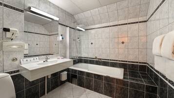 Un bany modern amb una banyera gran, un lavabo amb mirall i un vàter.