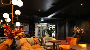 A modern lobby with a sofa, chairs, a table with candles, and a decorative vase.