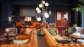 A cozy lounge area with a large sofa, a fireplace, and a modern chandelier.