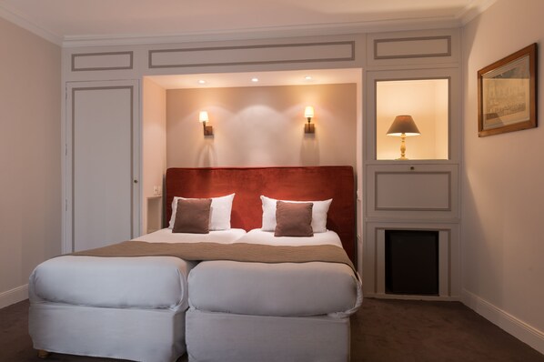 Une chambre d’hôtel avec un grand lit, deux lampes de chevet, une table de nuit et un tableau encadré au mur.