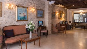 A cozy living room with a stone wall, wooden furniture, and artwork. - Hôtel Gaillon Opéra (Paris)