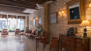 A spacious lobby with stone walls, wooden furniture, and a large mirror. - Hôtel Gaillon Opéra (Paris)
