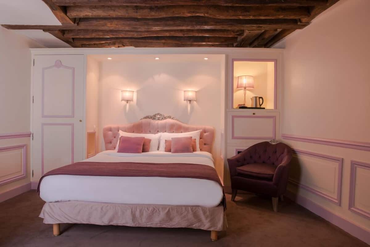 Un dormitorio con una cama grande, dos lámparas de pared, una silla y un espejo.