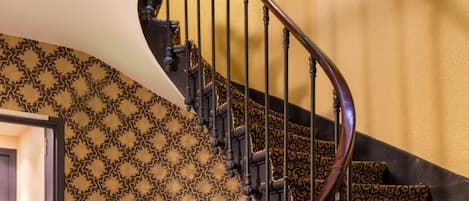 A spiral staircase with ornate metal railings and patterned carpet.