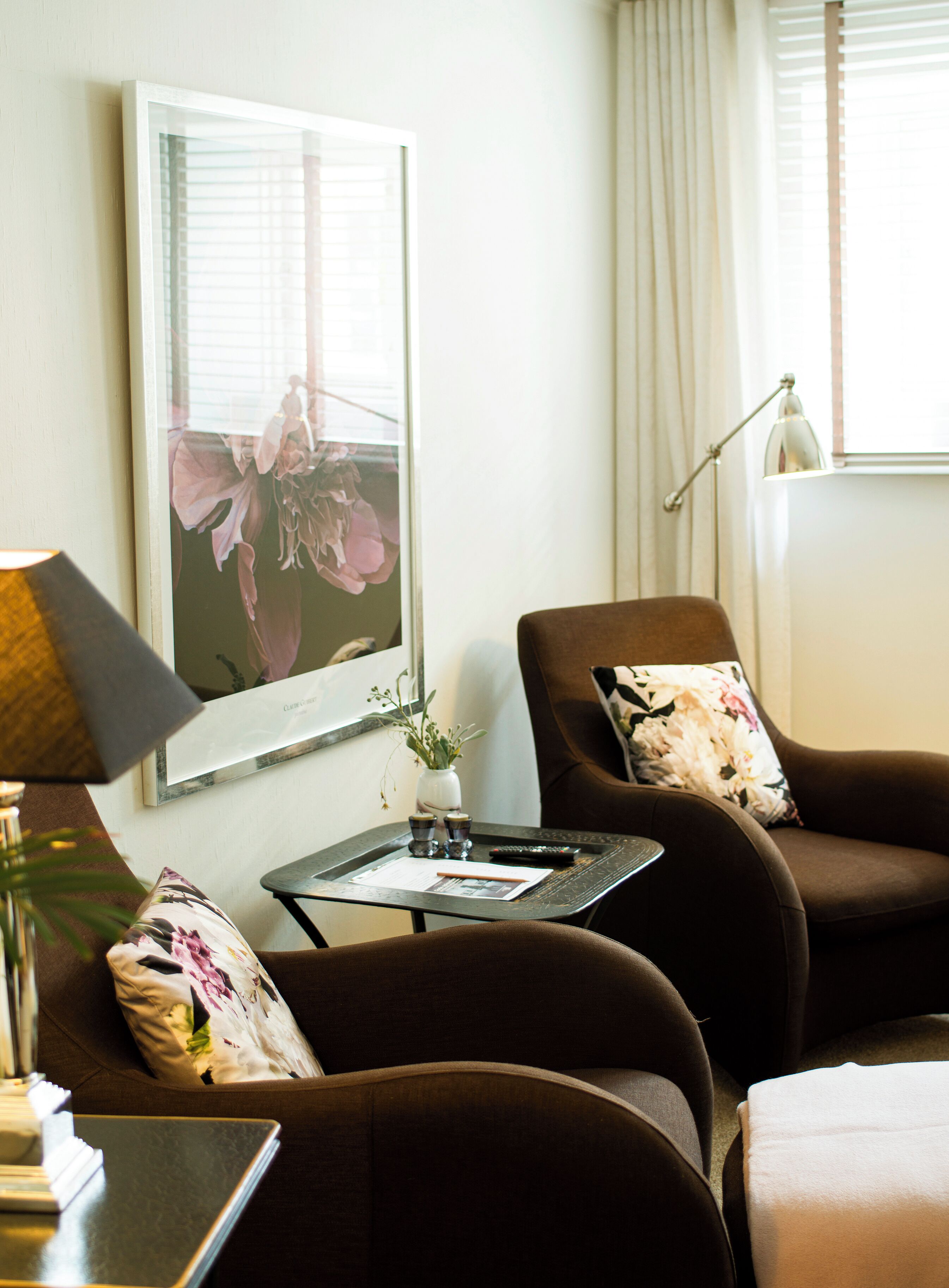 A living room with a brown sofa, a small side table, a lamp, and a framed picture on the wall.