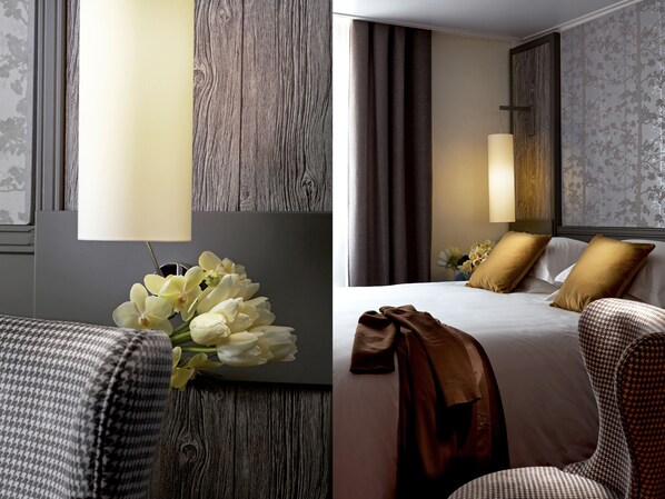 A hotel room with a wooden accent wall, a bed with white and brown bedding, and a lamp. - Hotel America (Cannes)