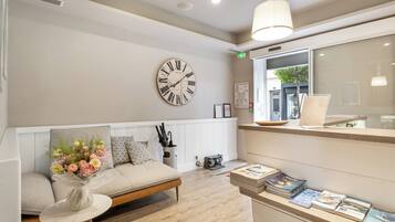 Un área de espera moderna con un banco de madera, un reloj de pared y un mueble para revistas.