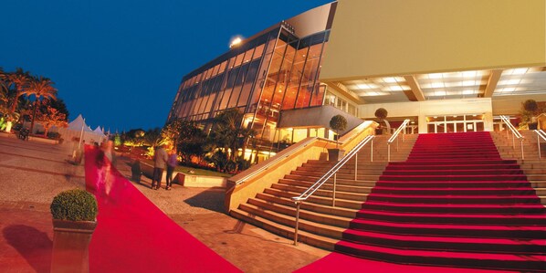 A modern building with a red carpeted staircase leading to an entrance. - Hotel America (Cannes)