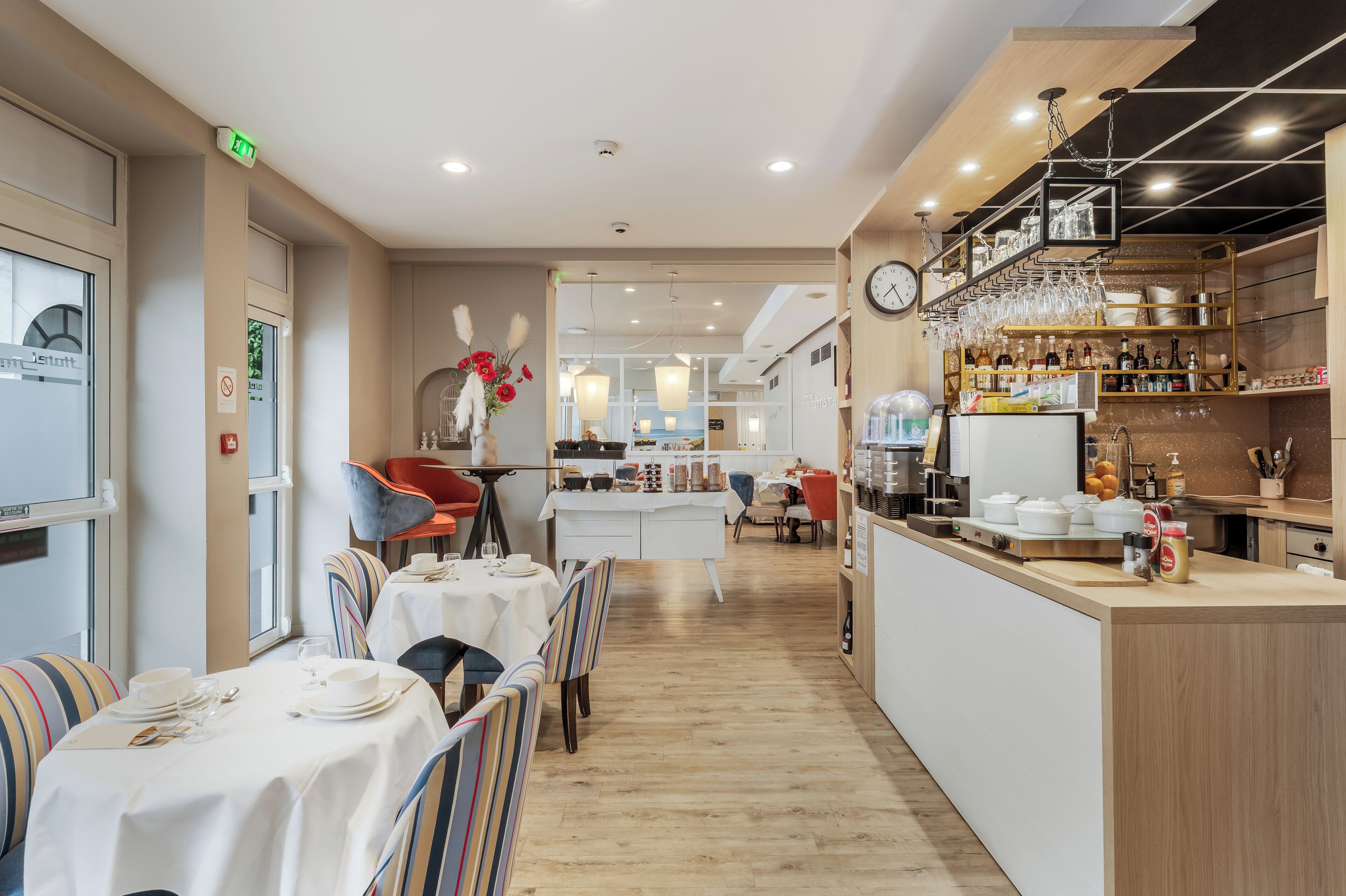 Un interior de restaurante moderno con una zona de comedor central, un bar y una cocina visible al fondo.