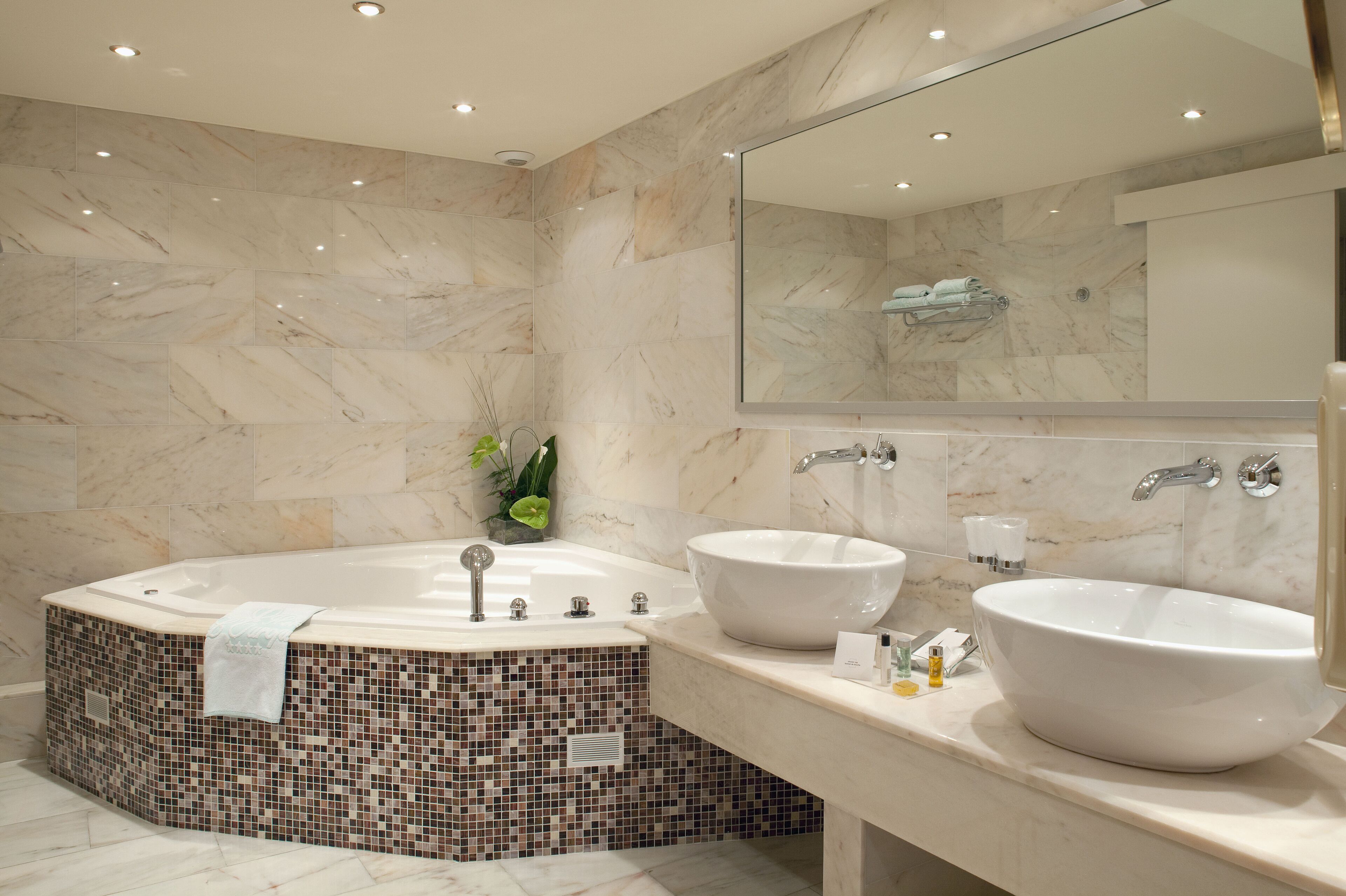 Une salle de bain moderne avec une baignoire sur pieds, deux lavabos et un grand miroir.
