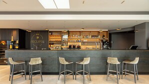 A modern bar with a dark counter, bar stools, and a variety of bottles and glasses. - Hotel L'Europe Colmar, BW Signature Collection (Horbourg-Wihr)