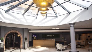 A modern hotel lobby with a reception desk, seating area, and a large skylight. - Hotel L'Europe Colmar, BW Signature Collection (Horbourg-Wihr)