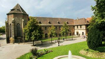 A historic building with a prominent tower, a courtyard with a fountain, and a well-maintained lawn.