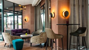 A modern lounge area with a sofa, chairs, a small table, and a bar stool. - Hotel L'Europe Colmar, BW Signature Collection (Horbourg-Wihr)
