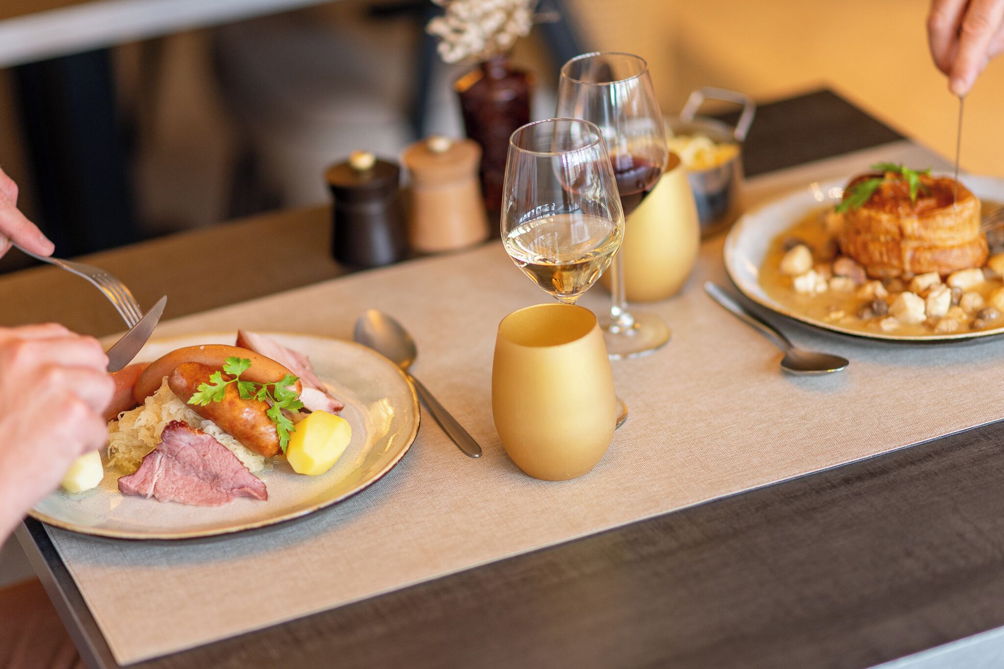 Una mesa de comedor con platos de comida, copas de vino y cubiertos.