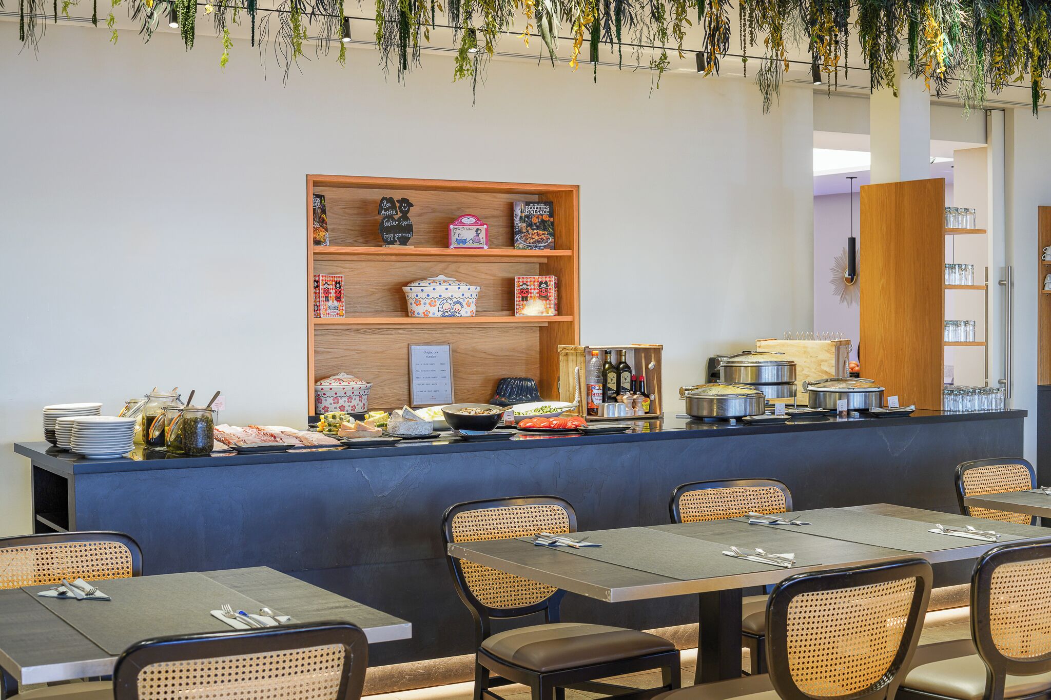 A buffet area with a wooden counter, wicker chairs, and tables set for dining.
