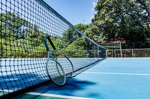 A tennis court with a net and a tennis racket leaning against it.